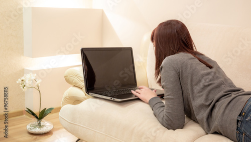 Woman on a couch using laptop at home with copy space