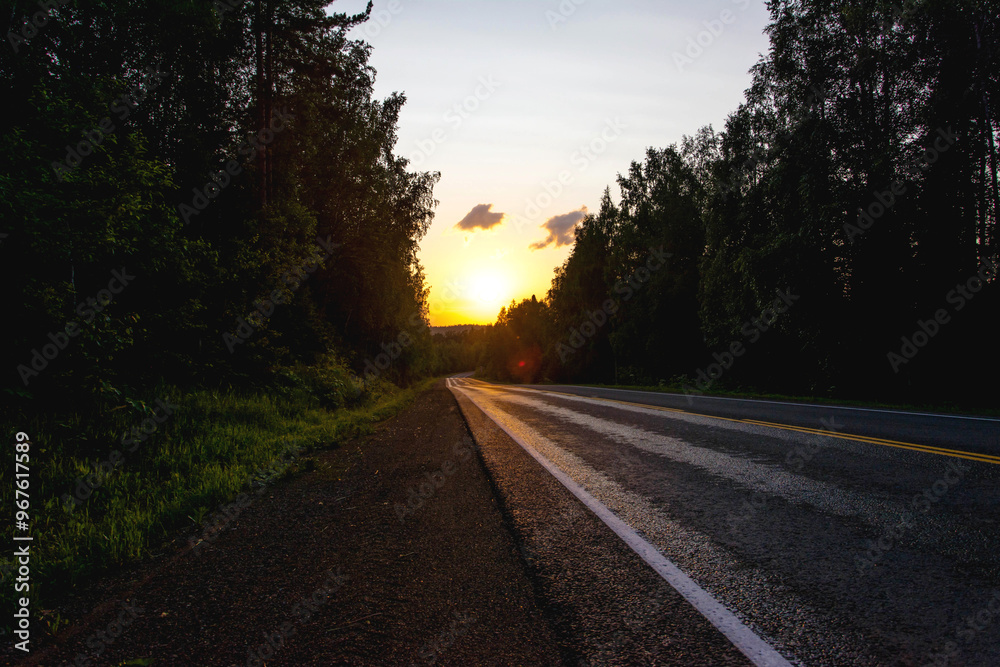 The roadbed glitter in the rays of the setting sun along the edges of the road is a forest of years The roadbed glitter in the rays of the setting sun along the edges of the road is a forest of years