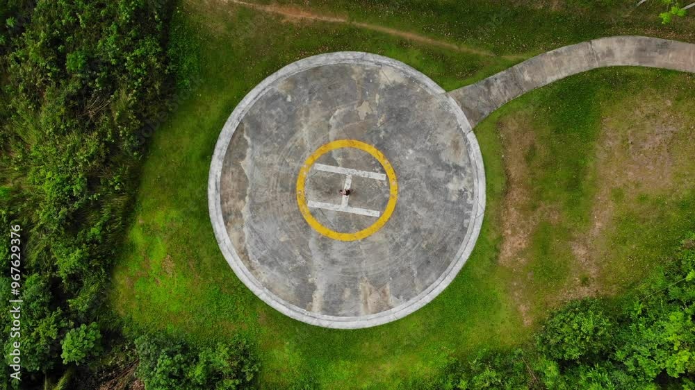 Aerial view of lush green helicopter platform with a woman and circular landing pad, Ko Yao Noi, Thailand. Aerial view of lush green helicopter platform with a woman and circular landing pad, Ko Yao Noi, Thailand.