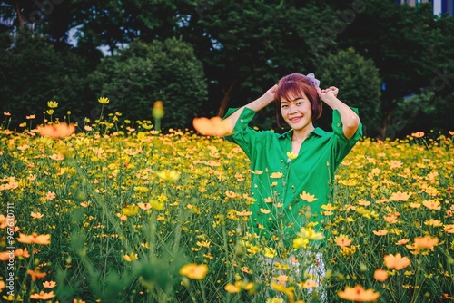 Woman posing happily in a yellow flower field, wearing a green dress photo