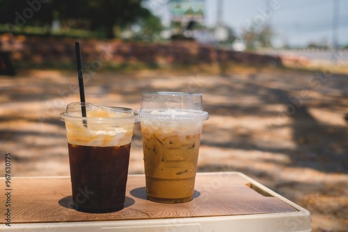 Two iced coffee drinks on a wooden table outdoors in the afternoon photo