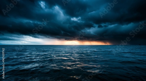 A dramatic seascape with dark stormy clouds and a sliver of golden sunlight breaking through.