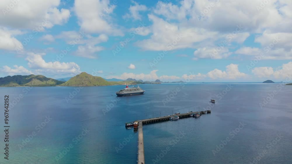 Aerial view of a serene tropical island with a pier, cruise ship, and boats on clear blue water, Komodo, Indonesia. Aerial view of a serene tropical island with a pier, cruise ship, and boats on clear blue water, Komodo, Indonesia.