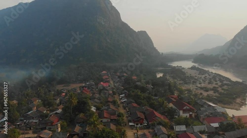 Aerial view of a picturesque village with traditional houses along a river and a dirt road, Muang Ngoy, Laos. photo