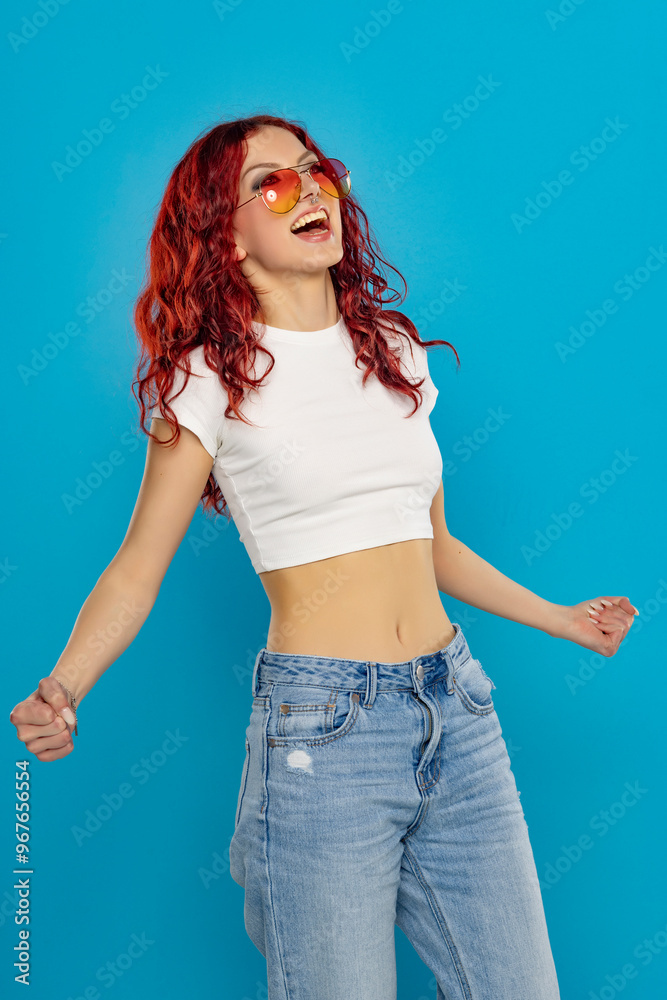 Φωτογραφία Portrait of a young happy woman in white shirt and long red wavy hair on a blue