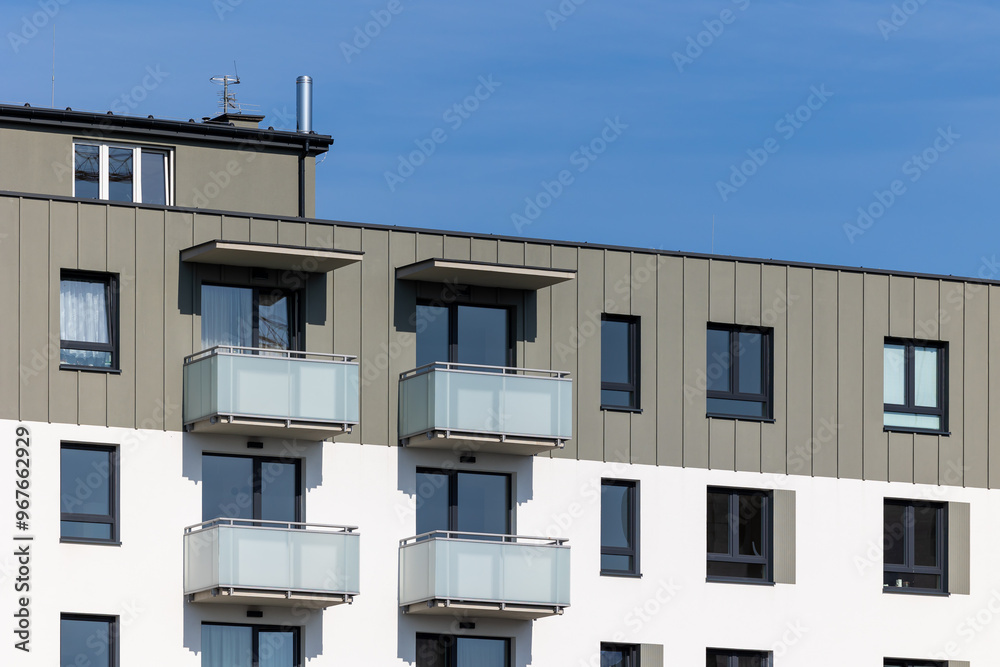 White and beige facade of a newly built apartment block. Clear blue sky above the building. Photo taken on a sunny day