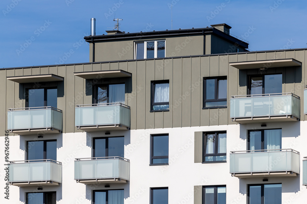White and beige facade of a newly built apartment block. Clear blue sky above the building. Photo taken on a sunny day