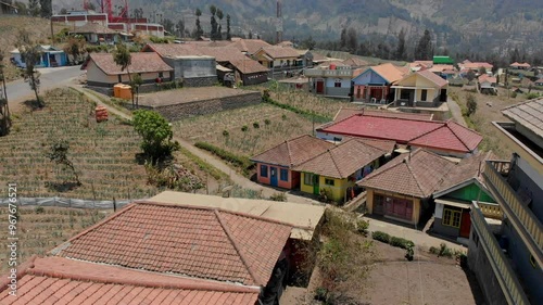 Aerial view of a beautiful village with traditional houses and antennas surrounded by scenic mountains and lush nature, Cemorolawang, East Java, Indonesia. photo