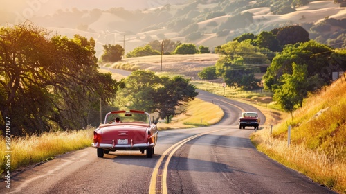 A picturesque road with classic cars driving through a scenic countryside, highlighting leisurely and recreational transportation. photo