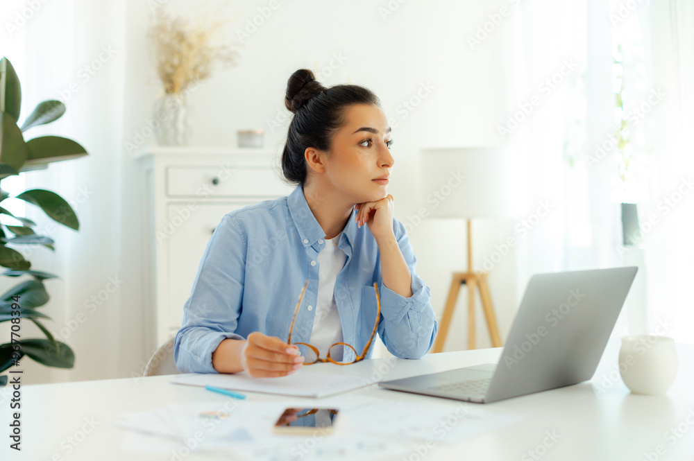 Frustrated worried business woman of arabian or indian ethnicity in blue a shirt, company ceo, sits at a workplace while working on a laptop, feels overworked and stressed, looks sadly away Frustrated worried business woman of arabian or indian ethnicity in blue a shirt, company ceo, sits at a workplace while working on a laptop, feels overworked and stressed, looks sadly away