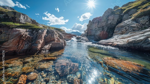 A stream cutting through a rocky canyon, with its clear waters sparkling under the bright sun, creating a dramatic landscape.