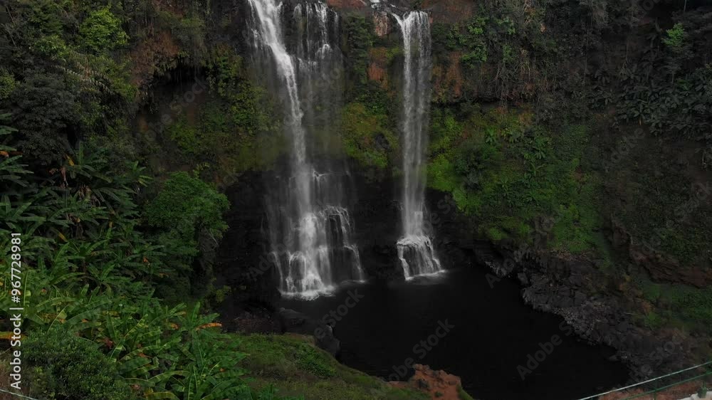 Aerial view of a breathtaking tropical waterfall cascading through lush green forest at sunset, Tad Gneuang, Champassak, Laos. Aerial view of a breathtaking tropical waterfall cascading through lush green forest at sunset, Tad Gneuang, Champassak, Laos.