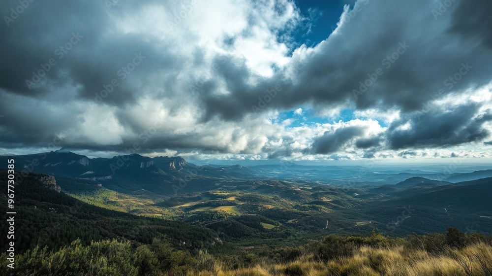 Fototapeta premium A panoramic view of a mountainous landscape under a dramatic sky with clouds.