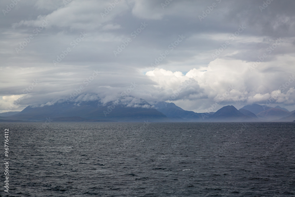 View of Scottish mainland from a ship, Image shows beautiful landscape coastal views of the mainland from a ship following the coastline image shows calm seas with heavy cloud and hilly terrain View of Scottish mainland from a ship, Image shows beautiful landscape coastal views of the mainland from a ship following the coastline image shows calm seas with heavy cloud and hilly terrain