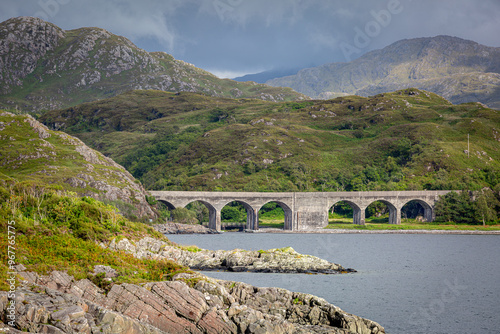 Loch nan Uamh viaduct from across the Loch, Image shows the viaduct located in Loch Nan Uamh on a summers day with clouds surrounding the mountains in the background photo