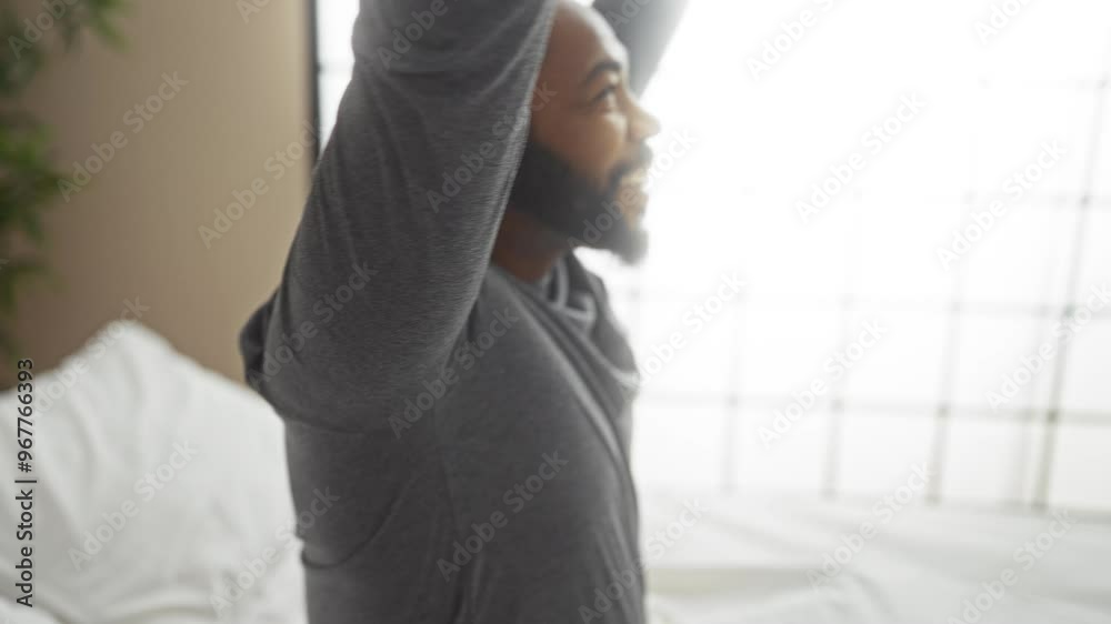 Young man waking up in bed, indoor bedroom setting with a dresser and window in the background Young man waking up in bed, indoor bedroom setting with a dresser and window in the background