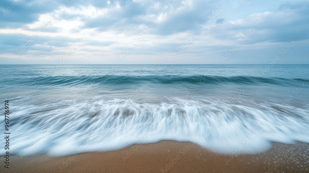 A serene beach scene with gentle waves lapping the shore under a cloudy sky. A serene beach scene with gentle waves lapping the shore under a cloudy sky.