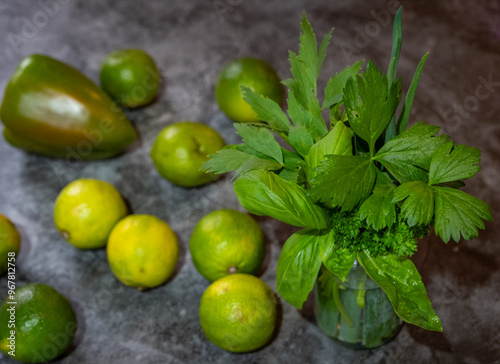 mehrere gelbe und grüne Limetten, Paprika und ein Kräuterglas Liebstöckel, Lauch, Basilikum, mit grauer Hintergrund, 
 photo