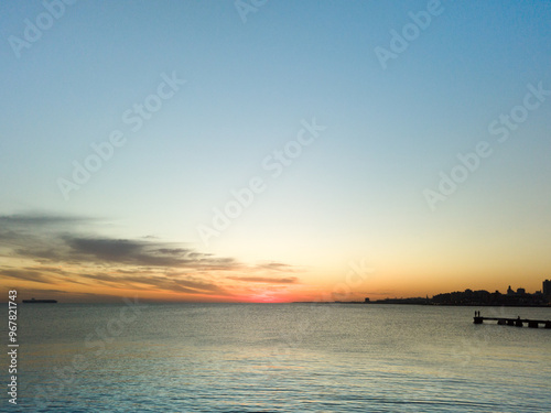 Montevideo City landscape at sunset, fishermen and cargo ship on the horizon.
