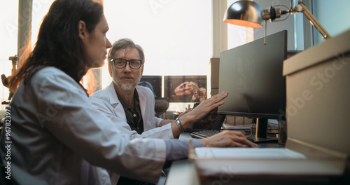 Photos Two diverse scientists discuss 3D visualization of ancient human head anatomy displayed on PC and tablet computer screen, conduct historical research