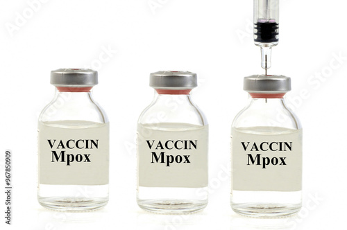 Concept vaccin variole du singe avec trois flacons de vaccin dont un percé avec une seringue en gros plan sur fond blanc