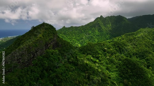 Aerial view of lush tropical mountain surrounded by serene sea and cloudy sky, Rarotonga, Cook Islands.