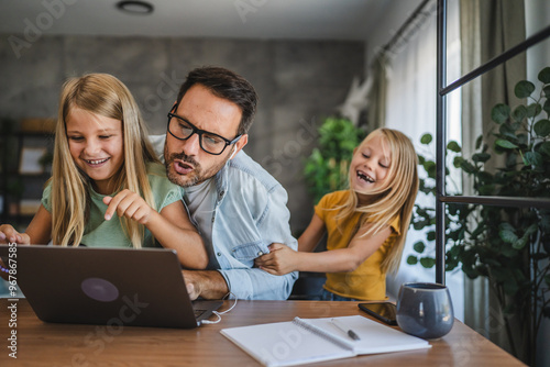 Father try to work from home while two daughters play around him