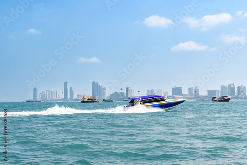 Speedboat sailing on the blue tropical sea on the background of Pattaya cityscape view and clear sky morning day at Koh Larn island. Speed boat running on the bay, Panorama ocean, Thailand, Vacation.