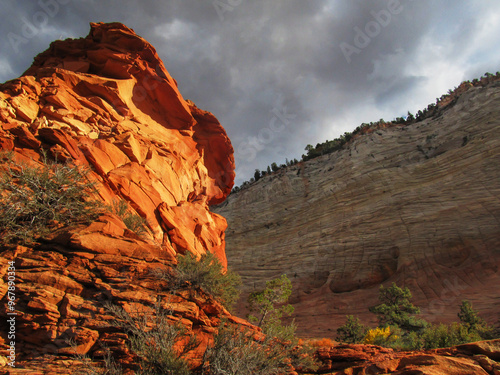 Golden red rock formation in the late afternoon sun with ominous clouds casting the cliffs in the background in shadow in Zion National Park of Utah. photo