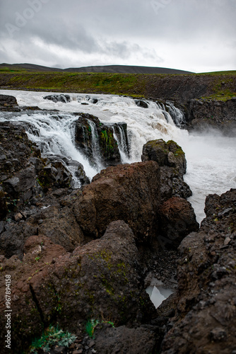 Majestic Waterfall in Rugged Terrain Under Cloudy Skies