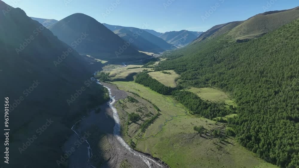 Aerial view of majestic Altai Mountains with a winding river and lush forest in a serene valley, Western Mongolia, Mongolia. Aerial view of majestic Altai Mountains with a winding river and lush forest in a serene valley, Western Mongolia, Mongolia.