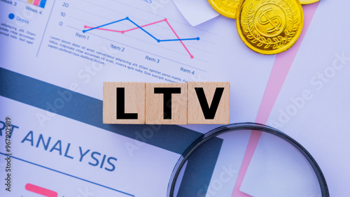 Three wooden cubes with the word LTV on graph sheets, abbreviation for Lifetime Value. Business profitability analysis, growth success, profitability. Business and financial market concepts.
