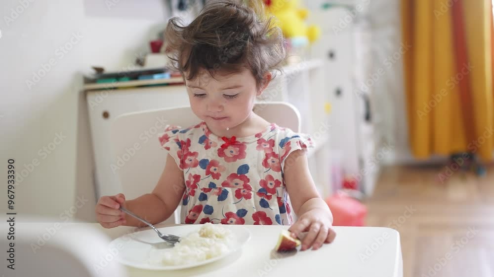 the girl eats at the table. happy family child dream concept. girl sits indoors at a white table and eats food with her hands holding an apple in his food hand. child's lifestyle the girl eats at the table. happy family child dream concept. girl sits indoors at a white table and eats food with her hands holding an apple in his food hand. child's lifestyle