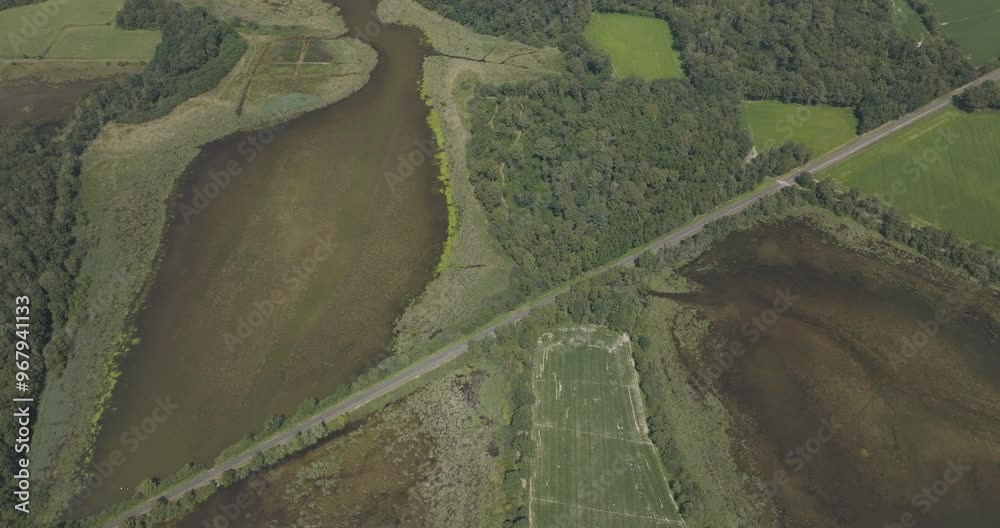 Aerial view of tranquil Parc des Oiseaux featuring lush greenery, river, and scenic fields, Marlieux, France.