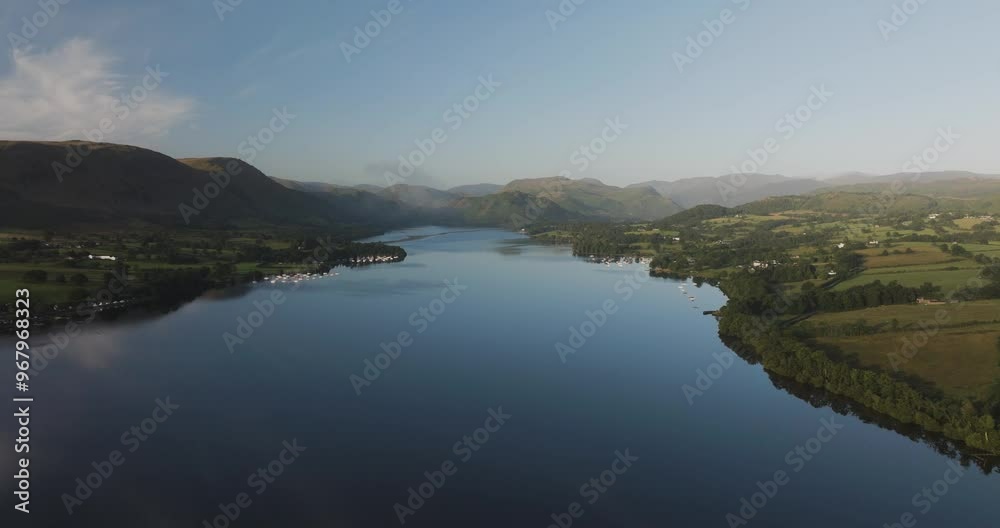 Aerial view of tranquil Ullswater lake surrounded by majestic mountains and lush greenery, Lake District, United Kingdom.