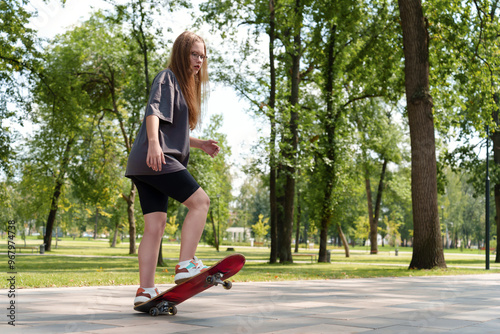 Young female skateboarder in t-shirt enjoying freedom of movement in natural setting. Representing active, adventurous lifestyle of teenagers during warm weather.