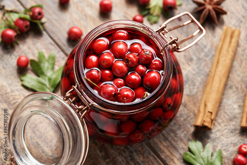 Macerating fresh hawthorn berries in red wine in a glass jar  - preparation of medicinal drink photo