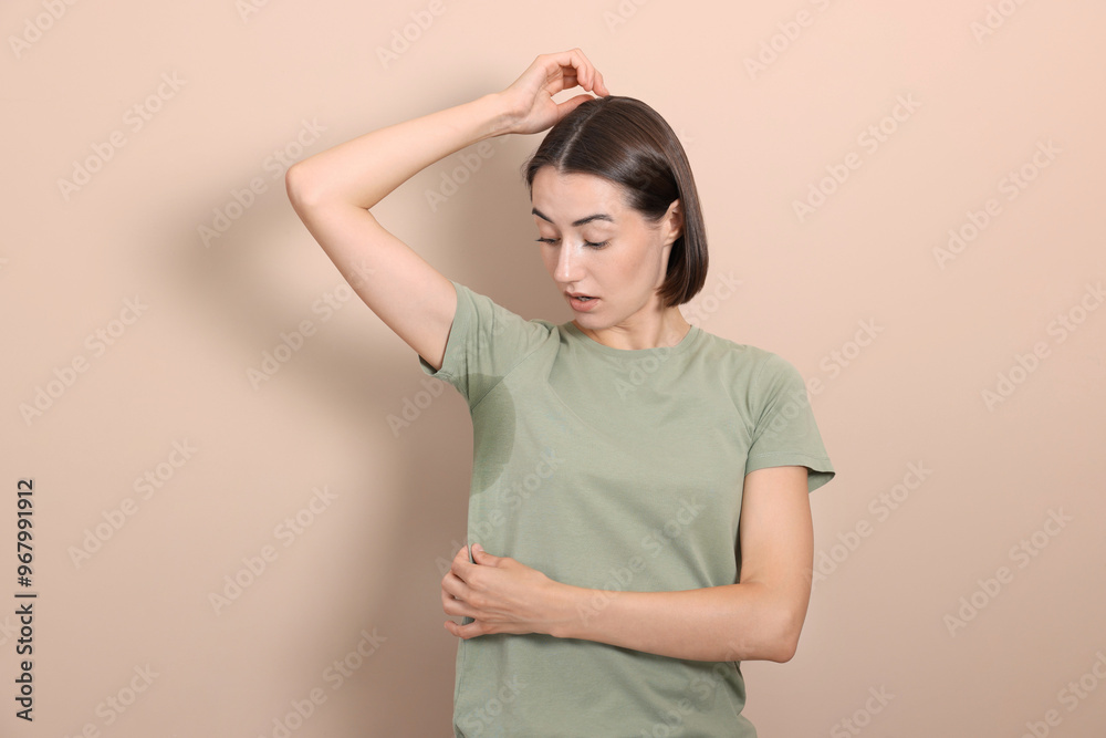 Emotional woman in t-shirt before using deodorant on beige background