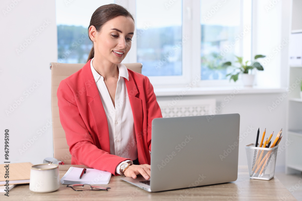 Smiling businesswoman working at table in office Smiling businesswoman working at table in office