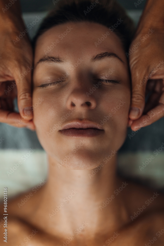 A woman receives a relaxing facial massage in a tranquil spa setting with soft warm lighting A woman receives a relaxing facial massage in a tranquil spa setting with soft warm lighting