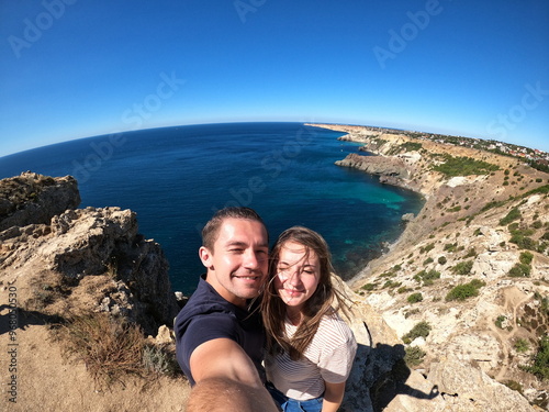 couple taking selfie on jangul landslide coast, crimea, beautiful sea cliff landscape, sunny summer day, travel adventure, scenic view, happy tourists, coastal exploration, nature photo