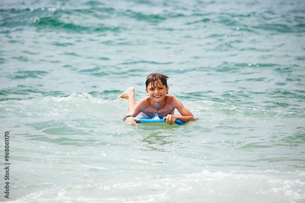 Teenage boy having a great time on blue bodyboard at the seaside Teenage boy having a great time on blue bodyboard at the seaside