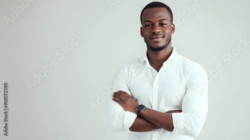 A man standing with a slight smile, arms crossed, exuding confidence on a light solid color background