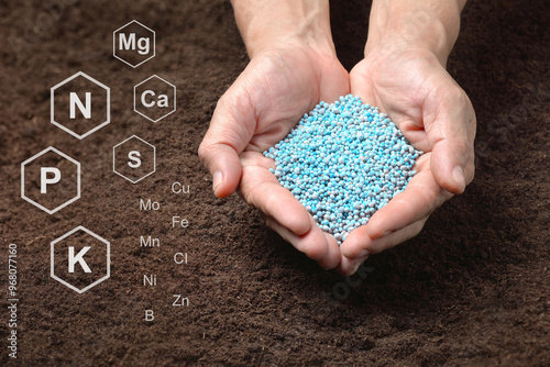 Chemical fertilizers in hand on soil background