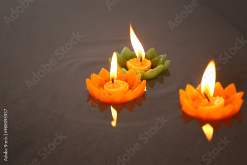 Candles of Krathong with flames floating on the water.