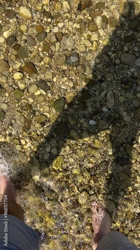 male feet walking in alpine river current in summer photo