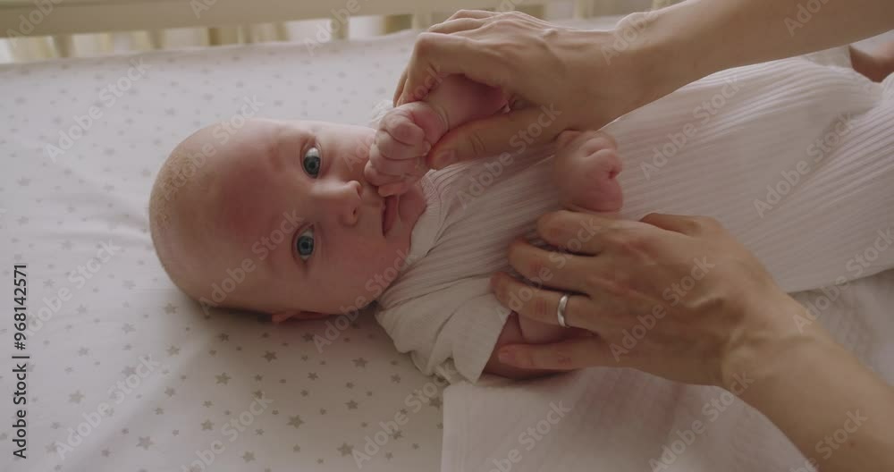 Happy mother spending time with infant baby, holding her little hands and talking tenderly. Cheerful mother playing with her newborn baby, tenderly holding little hands and sing funny song.