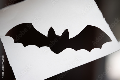 Foto silueta de murciélago recortada en papel blanco con fondo negro