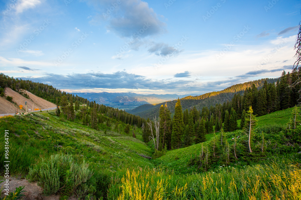 Fototapeta premium Scenic mountain road winding through a lush valley under sunset sky