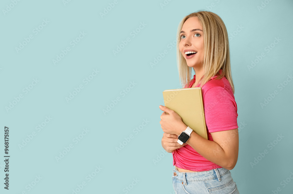 Beautiful young happy woman with book on blue background